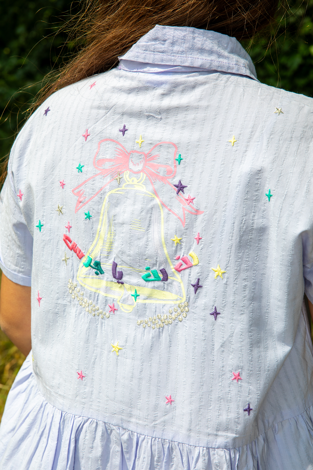 Light blue dress with embroidered colorful bell and stars design on the back