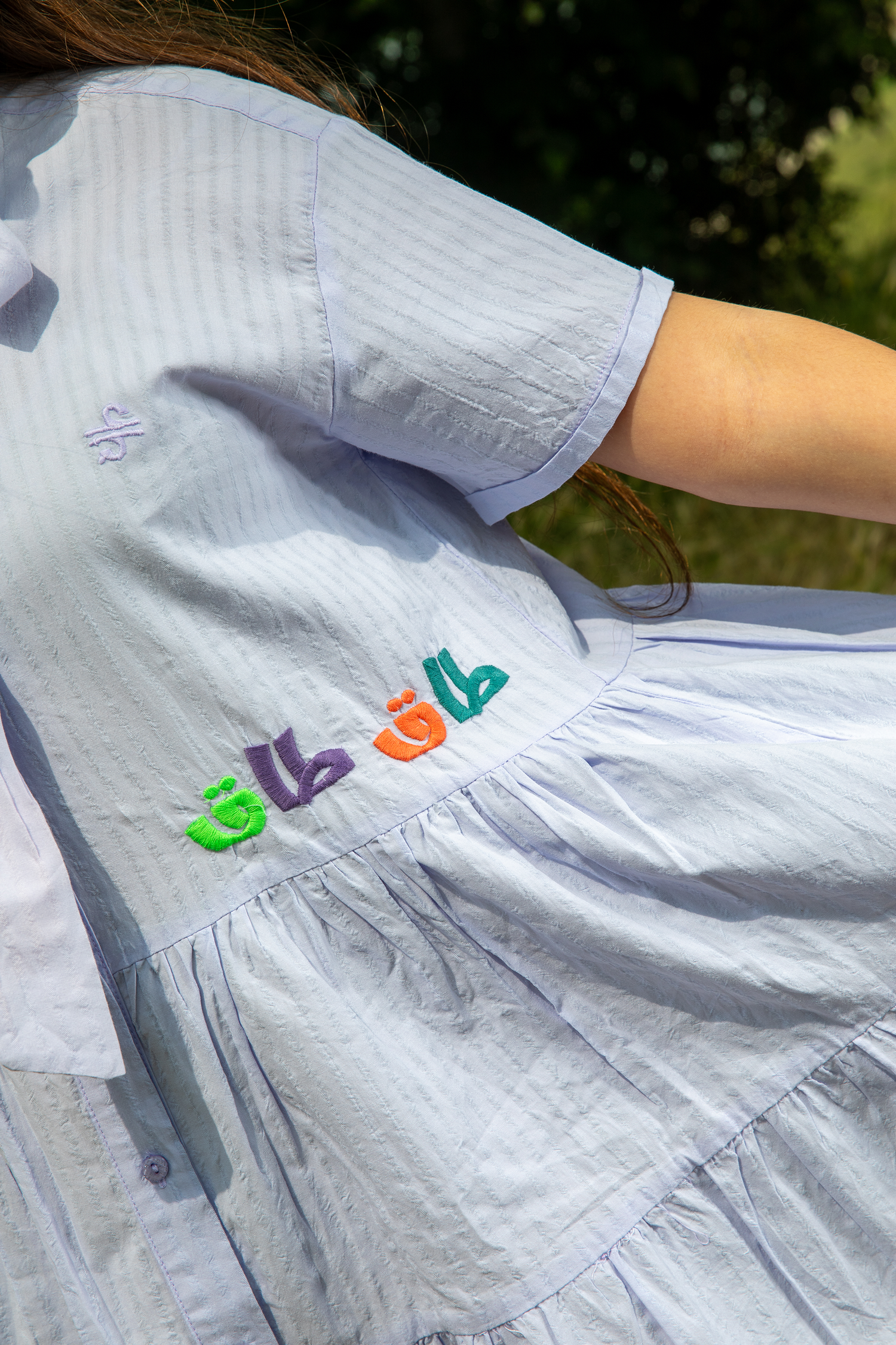 Light blue dress with colorful embroidered Arabic calligraphy detail on the back