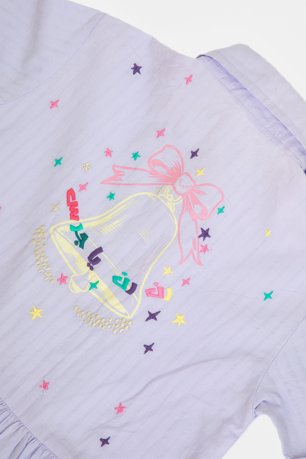 Light purple shirt with colorful embroidered bell and bow design with stars
